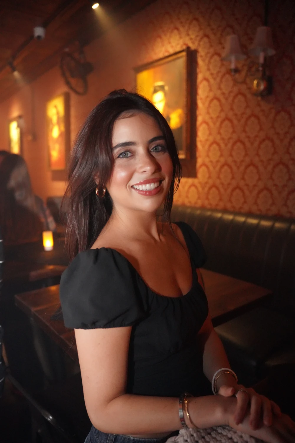 A smiling guest photographed beside warm lighting and a restaurant booth
